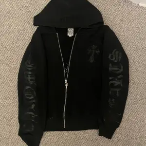 Säljer en svart hoodie från Chrome Hearts i bra skick. Den har en dragkedja framtill och  tryck på både ärmar och rygg. Perfekt för höst och vår, med en normal passform och långa ärmar.