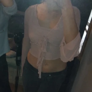 Rosa croppad topp med knyt - Säljer en söt rosa croppad topp med knyt framtill. Toppen har långa ärmar och en lätt volangdetalj vid ärmsluten. Perfekt för en somrig look eller en utekväll med vänner!