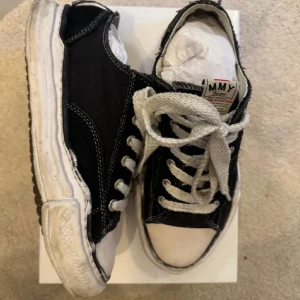 Svarta sneakers med vita detaljer - Säljer ett par svarta sneakers från MMY i bra skick. De har vita snören och en vit sula som ger en snygg kontrast. Perfekta för vardagsbruk och passar till de flesta outfits. Skorna har en klassisk design med snörning och är bekväma att gå i.