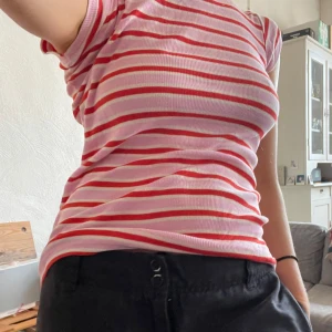 Randig topp från Mads Nørgaard - Säljer en superfin randig topp från Mads Nørgaard i rosa och rött. Den är ribbad och har korta ärmar. Toppen är i mycket bra skick och passar perfekt till jeans eller kjol. Skicka ett meddelande vid intresse!