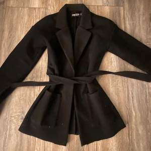 Svart kappa  - Säljer en jätte söt  svart kappa från nelly/pieces. Det är liten i storleken! Jag är 162. Pris kan diskuteras! 🥰