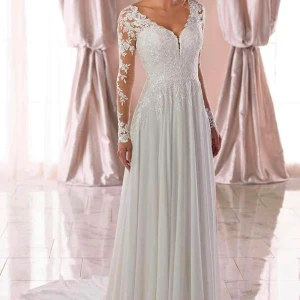 Vit långklänning med spetsdetaljer - Elegant vit långklänning med vackra spetsdetaljer och långärmade ärmar. Klänningen har en öppen rygg och en v-ringad halslinje, vilket ger en romantisk och sofistikerad look. Perfekt för sin bröllop🥰Helt ny endast provad.