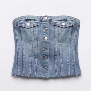 Jeanskorsett med knappar - aldrig använd, nypris 329kr. Snygg jeanskorsett i blått med knappar framtill och dekorativa fickor. Den är axelbandslös och har en tight passform. Passar perfekt till både vardag och fest!