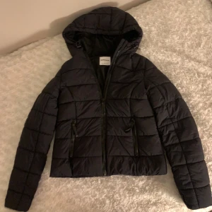 Svart pufferjacka från Bershka - Säljer en svart pufferjacka från Bershka i storlek S. Jackan har en dragkedja framtill och en mysig bra sittande huva. Har använt endast fåtal gånger. Fråga om ni vill ha mer bilder