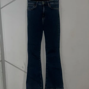 Blå Peachy Flare Jeans - Säljer ett par snygga blå Peachy Flare jeans i storlek S. De har en hög midja och en cool bootcut-stil som ger en retro vibe. Perfekta för både vardag och fest! De är i mycket bra skick och har en klassisk femficksdesign.