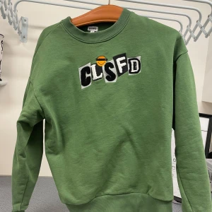 Grön sweatshirt från Classified - Säljer en snygg grön sweatshirt från Classified med fluffigt tryck på framsidan. Tröjan har en normal passform(kanske något kort) och är perfekt för alla säsonger. Den är i mycket bra skick och superbekväm att ha på sig. Tröjan är från ett limiterat släpp. Bara att kontakta om man har frågor. Nypris: 799 