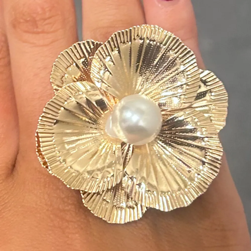 Superfin guldfärgad ring formad som en blomma med en stor pärla i mitten. Perfekt för att ge en extra touch till din outfit. Ringen har en glittrig yta som fångar ljuset snyggt. Köpte på en marknad i Mallorca💝💝. Accessoarer.