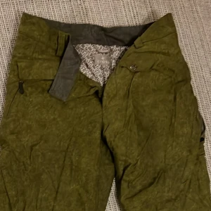 Gröna byxor🥑 från CROSS - Säljer ett par gröna skidbyxor från CROSS. De har en cool,figursydd look och en knappdetalj vid midjan. Perfekta för en avslappnad stil eller en dag ute i naturen. Passar bra till skid och vintersäsongen.