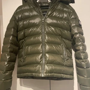 Olivgrön pufferjacka från Bvaldi - Pris går att diskuteras! Säljer en snygg olivgrön pufferjacka från Bvaldi. Jackan har en dragkedja framtill och en mysig huva. Perfekt för kyliga dagar med sin quiltade design som håller värmen. Den är i helt ny och passar perfekt för höst och vinter. Storleken är S jag är 177 och väger 60kg och passar mig fint
