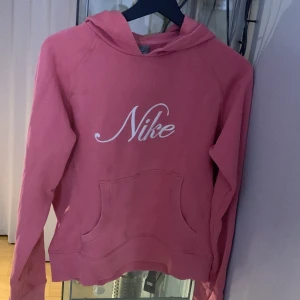 Rosa hoodie från Nike - Säljer en superfin rosa hoodie från Nike i storlek 158-170 från barn avdelningen. Den är i bra skick och använt ett fåtal gånger. Perfekt för mysiga dagar eller en avslappnad stil. Huvan ger extra värme och komfort. Passar perfekt till jeans eller leggings! 