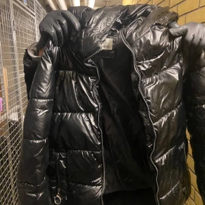 Svart pufferjacka från Xuelijiabao - Säljer en svart pufferjacka från Xuelijiabao. Jackan är i bra skick, men den har hål vid fickorna(kolla bild). Den har en glansig yta med dragkedja framtill. Passar perfekt för höst och vinter! Det är storlek S/M💕