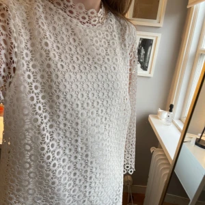 Vit spetsblus - Säljer en superfin vit spetsblus med blommigt mönster. Blusen har långa ärmar och en rak passform som ger en elegant look. Perfekt för vår och sommar, både till vardags och fest. Den är i mycket bra skick och redo för en ny ägare!