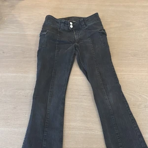 Svarta bootcut jeans från H&M - Säljer ett par svarta bootcut jeans från H&M i storlek EUR 164. De har fickor på sidan med knappar. De har justerbar midja och är lågmidjade. Perfekta för en snygg outfit med en fin passform. Använda men i bra skick!🩷🩷