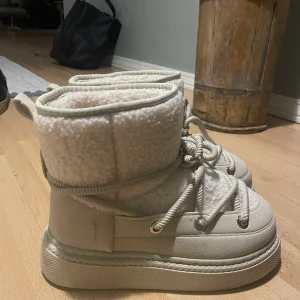 Beige vinterboots med snörning - Säljer ett par mysiga inuikii inspirerade beiga vinterboots som är perfekta till kalla dagar. Vet tyvärr inte märke då jag fått de i present & inte kunde ha de. Endast testade, aldrig använda🤍