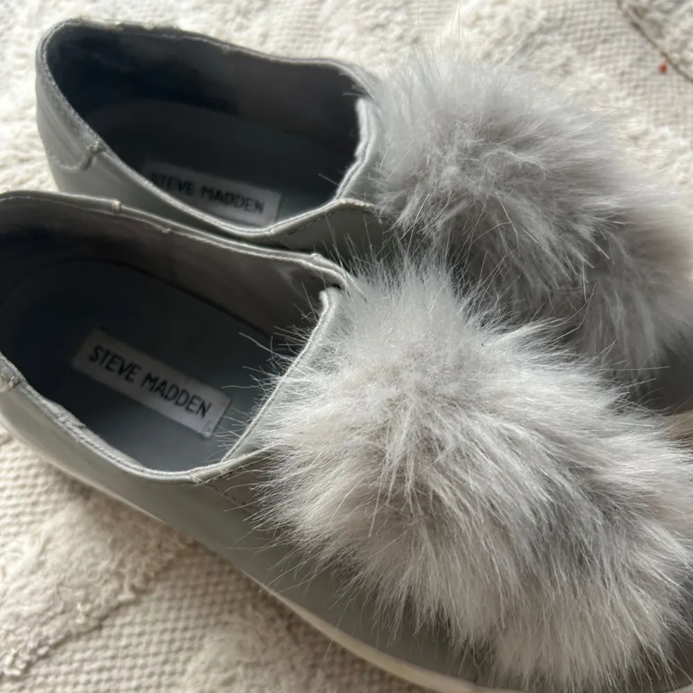 Säljer ett par grå sneakers från Steve Madden i bra skick. De har en unik och fluffig pälsdetalj på ovansidan som ger en cool touch. Perfekta för att liva upp vardagslooken! Skorna är bekväma och lätta att ta på 💗. Skor.