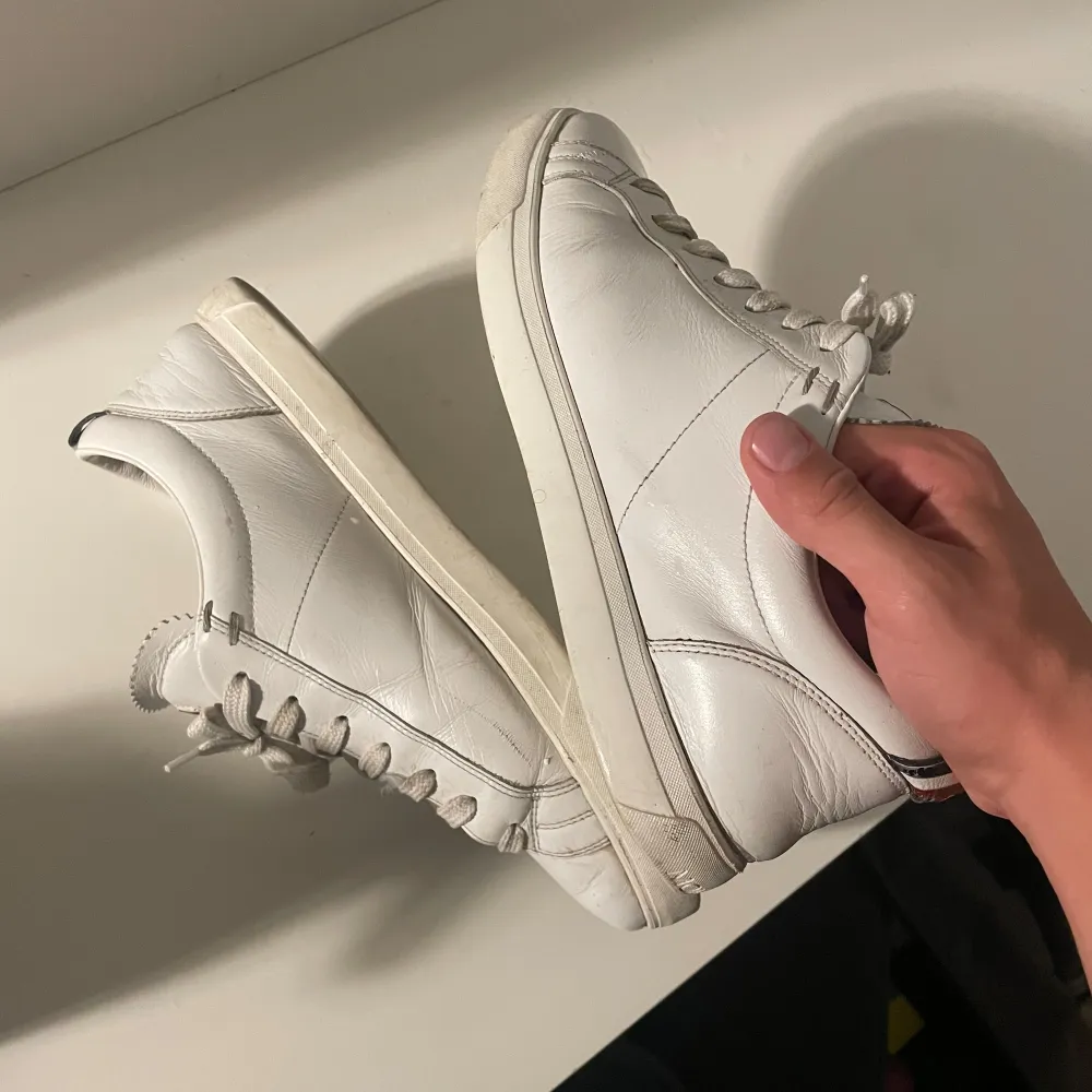 Säljer ett par stilrena vita sneakers från Moncler i skinn. De har klassisk snörning och en bekväm passform. Perfekta för både vardag och festliga tillfällen. Skorna kommer med originalkartong och dustbag. Använda men i bra skick. Storlek 41 men passar 42 och 42,5. Skor.