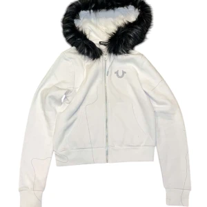 True Religion Hoodie - Snygg vit True Religion hoodie med svart päls som har gråa och vita detaljer, perfekt till kalla vinterdagar!