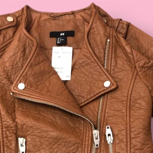 läderjacka H&M - Säljer en oanvänd läderjacka i kort modell från H&M. Ordinrie pris 499 sek. Den är i storlek 34 och har en ljusbrun eller kastanjefärg. Perfekt för att ge din outfit ett stiligt lyft! Kontakta mig för mer information eller bilder. Titta gärna på mina andra annonser också!