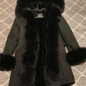 Jacka  - Säljer en snygg svart parkajacka med lyxiga pälsdetaljer på huva, ärmslut och längs med dragkedjan. Perfekt för kalla vinterdagar och håller dig varm och stilren. Pälsen går att ta av, använd ett fåtal gånger. 