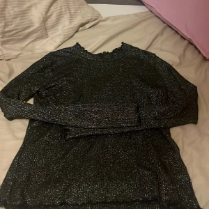 Svart glittrig tröja från H&M - Säljer en snygg svart glittrig tröja från H&M. Perfekt för festliga tillfällen med sin glittriga look. Tröjan har långa ärmar och en bekväm passform. Passar perfekt till både jeans och kjol för en stilren outfit. Hör av dig vid intresse! ✨