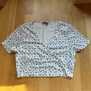 Säljer en söt vit omlottopp från Shein med blå blommor köpt second hand men i toppen skick. Toppen är kortärmad och har en v-ringad design. Materialet är mjukt och stretchigt med 95% polyester och 5% spandex. 💙