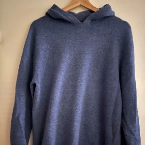 Merinoull Hoodie  - Säljer en supermjuk och varm blå hoodie i merinoull. Perfekt för kyliga dagar med sin sköna passform och långa ärmar. Den har en praktisk huva och ribbade muddar vid ärmslut och nederkant. Perfekt för både höst och vinter! Jag har tagit bort luvsnörerna men dom är lätt att sätta på. Tröjan är köpt från Gardegrisch för över 1000kr och är i storlek M.