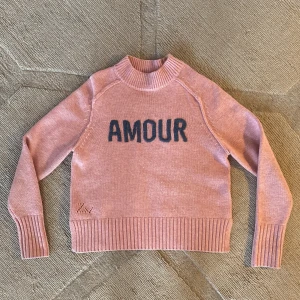 Zadig & Voltaire - oanvänd stickad tröja - Oanvänd snygg stickad tröja från Zadig & Voltaire designad med ribbstickade muddar och texten AMOUR på bröstet. Perfekt till både jeans och kjol! 
