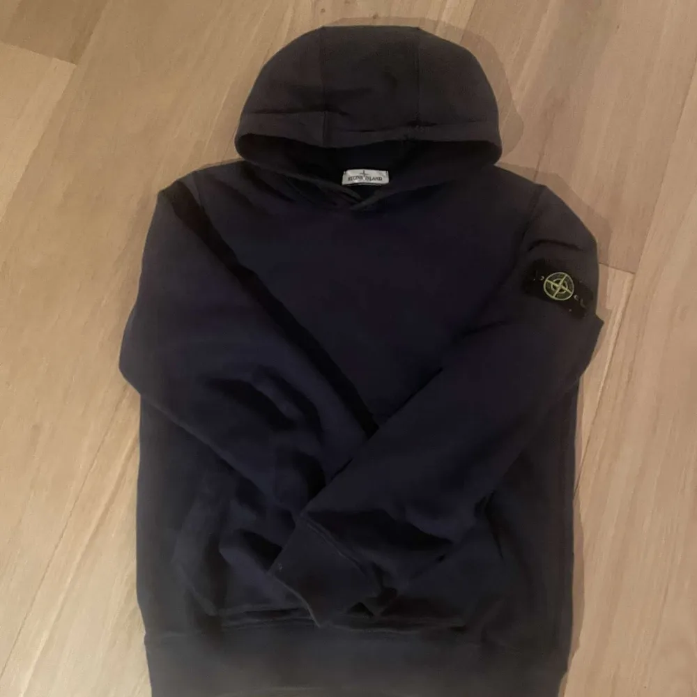 Säljer en snygg svart hoodie från Stone Island. Den har en klassisk design med en huva och en ikonisk logga på ärmen. Perfekt för både vardag och chill. Passar bra till jeans eller joggers. Hör av dig vid intresse eller vid minsta fundering🙌. Tröjor & Koftor.