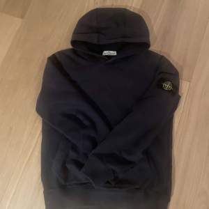 Säljer en snygg svart hoodie från Stone Island. Den har en klassisk design med en huva och en ikonisk logga på ärmen. Perfekt för både vardag och chill. Passar bra till jeans eller joggers. Hör av dig vid intresse eller vid minsta fundering🙌