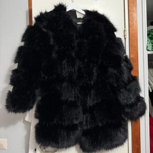 Svart pälsjacka - Säljer en superfluffig svart pälsjacka som är perfekt för vintern. Den har en oversized passform och långa ärmar, vilket gör den både stilren och mysig. Jackan är i mycket bra skick och passar perfekt för både fest och vardag. Ett måste för garderoben om du vill hålla dig varm och trendig!