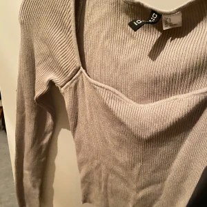 Beige ribbad topp från Zara - Säljer en snygg beige ribbad topp från Zara i storlek S. Toppen har en v-ringad design och långa ärmar, perfekt för både vardag och fest. Den är i bra skick och passar utmärkt till höst- och vårgarderoben.