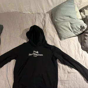 Svart hoodie från Peak Performance - Säljer en svart hoodie från Peak Performance i storlek 170. Den är i bra skick och har en klassisk design med logga på bröstet. Perfekt för höst och vinter, och passar både till vardags och träning. Superbekväm och stilren! 🖤