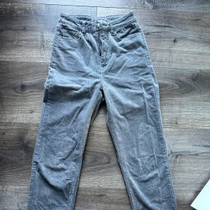 Grå manchesterbyxor - Säljer ett par snygga grå manchesterbyxor i bra skick. De har en klassisk femficksdesign med knapp och dragkedja framtill. Perfekta för höst och vinter, och de ger en skön retrovibe. 