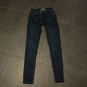 Mörkblå super skinny jeans - Säljer ett par mörkblå super skinny jeans i storlek 26. De är i bra skick och perfekta för både vardag och fest. Passformen är tight och de har en klassisk femficksdesign med dragkedja och knapp. Perfekta för dig som gillar en stilren look!