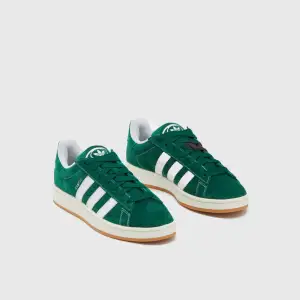 Säljer ett par snygga gröna Adidas Campus sneakers i mocka. De har de klassiska vita ränderna och en bekväm gummisula. Perfekta för både vardag och fest! Skorna är använda en gång och är i ett mycket bra skick. Dem gröna snöret kommer även med vid köpet men det är dem vita snörena som är i nu