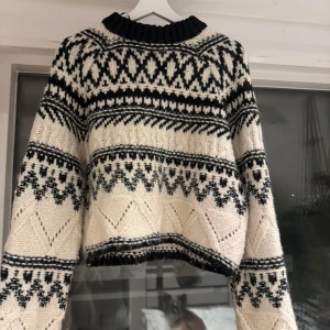 Svartvit stickad tröja - Säljer en superfin svartvit stickad tröja med ett snyggt geometriskt mönster. Tröjan är croppad och har långa ärmar, perfekt för höst och vinter. Den är både mysig och stilren, perfekt för att hålla sig varm och trendig. Passar lika bra till jeans som till kjol!
