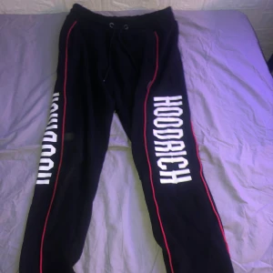 Svarta mjukisbyxor från Hoodrich - Säljer ett par svarta mjukisbyxor från Hoodrich i storlek XS. Byxorna har vita tryck längs benen och röda detaljer. De är tillverkade i 100% bomull vilket gör dem superbekväma. Perfekta för en avslappnad stil eller träning. 🖤