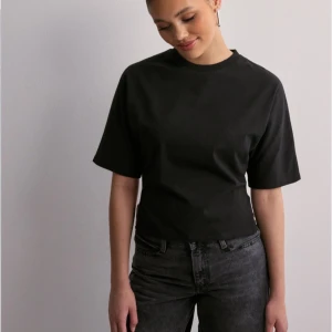 Svart kortärmad topp med knyt - Snygg svart topp med korta ärmar och en cool knytning i ryggen. Perfekt för en avslappnad men stilren look. Passar bra till jeans eller kjol för en trendig outfit.