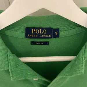 Säljer en snygg grön pikétröja från Ralph Lauren i storlek S. Den har en klassisk krage och korta ärmar, perfekt för sommaren. Tröjan är slim fit och har det ikoniska rosa broderade logotypen på bröstet. Perfekt för en stilren och avslappnad look! 🌿