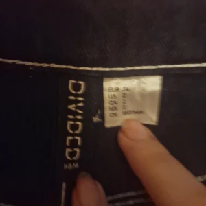 Svarta cargopants från H&M Divided - Säljer ett par svarta cargopants från H&M Divided i storlek 34. Byxorna har vita kontrastsömmar och flera praktiska fickor på sidorna. Perfekta för en avslappnad och trendig look. De är i bra skick och redo för nya äventyr! Pris kan diskuteras.