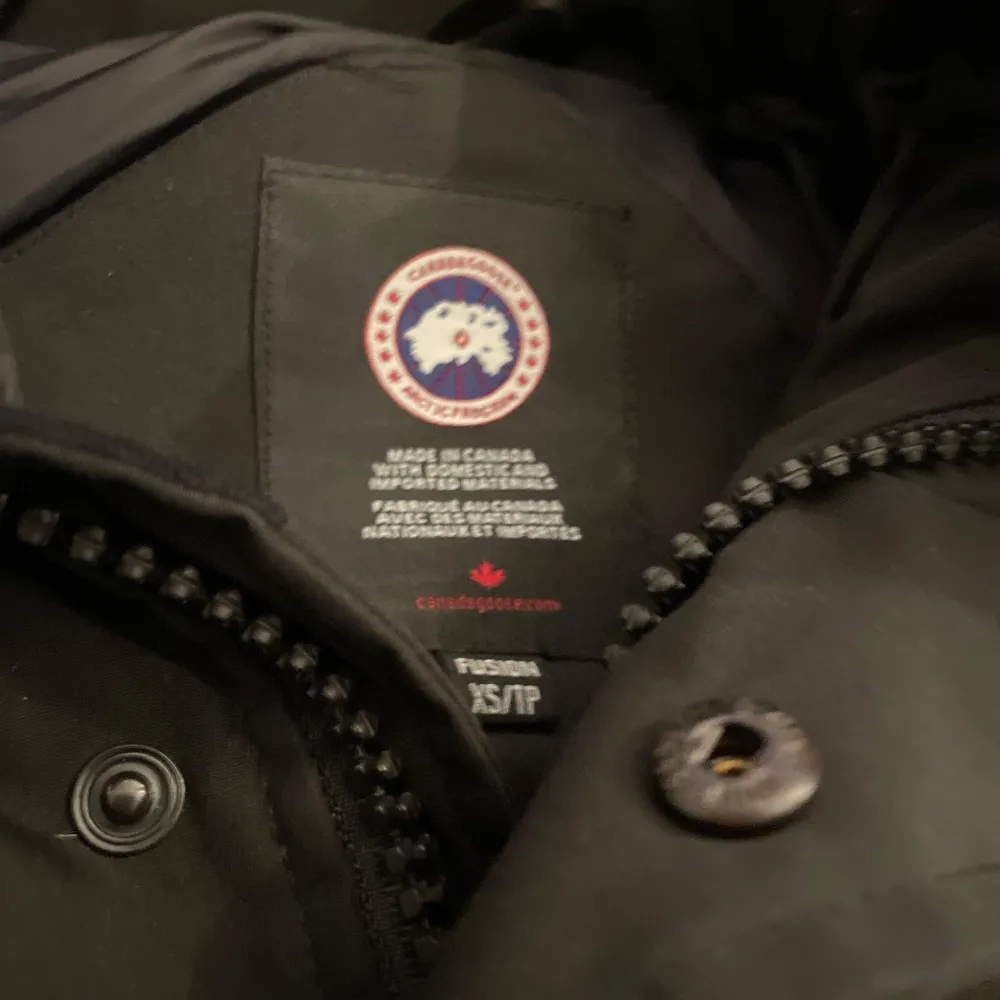 Säljer en svart dunjacka från Canada Goose i mycket bra skick. Jackan har en varm och vadderad design med huva och knappar. Perfekt för kalla vinterdagar. Den är långärmad och har en klassisk stil som passar till det mesta. Hög kvalitet och superbekväm!. Jackor.