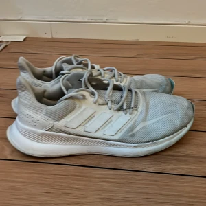Vita Adidas löparskor - Säljer ett par vita Adidas sneakers i bra skick. De har en stilren design med snörning och är perfekta för träning eller vardagsbruk. Skorna är tillverkade i syntetmaterial och har en bekväm passform. 
