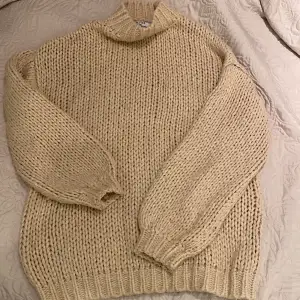 Mysig beige stickad tröja i tjockt garn, perfekt för kyliga dagar. Den har en hög krage och långa ärmar med ribbstickade muddar. Passar bra till både vardag och mysiga hemmakvällar. 🧶