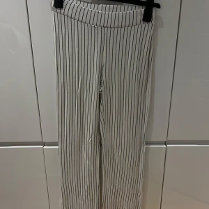 Randiga byxor i vitt och svart - Säljer ett par snygga randiga byxor i vitt och svart. De har en hög midja och en straight passform som ger en stilren look. Perfekta för både vardag och fest! 🖤🤍