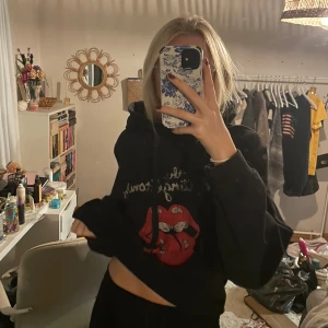 Svart hoodie med tryck - Säljer en svart hoodie med ett coolt tryck av the rolling stones . Perfekt för en avslappnad stil och att hålla sig varm. Den har en klassisk passform med långa ärmar och en bekväm huva. Perfekt för höst och vinter!