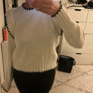 Vit stickad tröja med volangdetaljer -  Superfin vit stickad tröja med svarta volangdetaljer från reserved. Aldrig använd där av super fint skick!🌟Perfekt nu till höst och vinter.