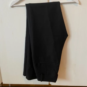 Svarta kostymbyxor - Snygga svarta kostymbyxor med hög midja och straight passform. Perfekta för både kontoret och festliga tillfällen. De är stilrena och enkla att matcha med olika toppar och skor. Är i storlek 34 