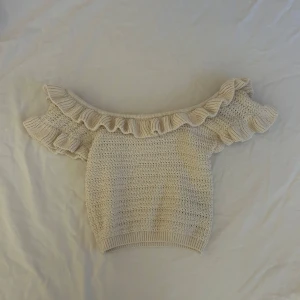 Beige stickad topp från H&M - Säljer en superfin beige stickad topp från H&M i storlek XS. Den har en offshoulder-design med volangdetaljer runt halsen och ärmarna! 🧡