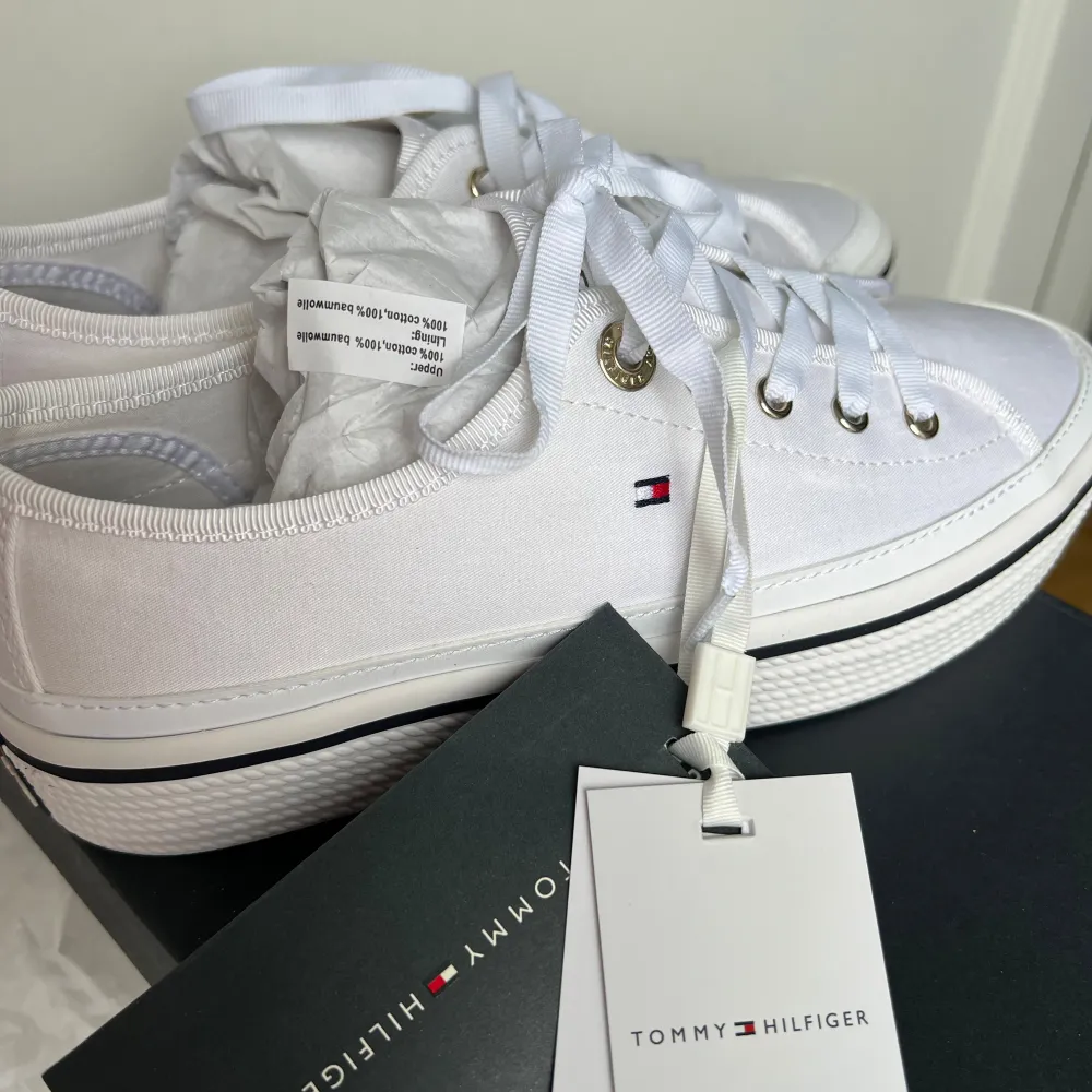 Säljer ett par snygga vita sneakers från Tommy Hilfiger i nytt skick. De har en klassisk design med snörning och en liten logga på sidan. Perfekta för vår och sommar, och passar till nästan alla outfits. Skorna är i storlek dam 39 och kommer i originalförpackning.. Skor.