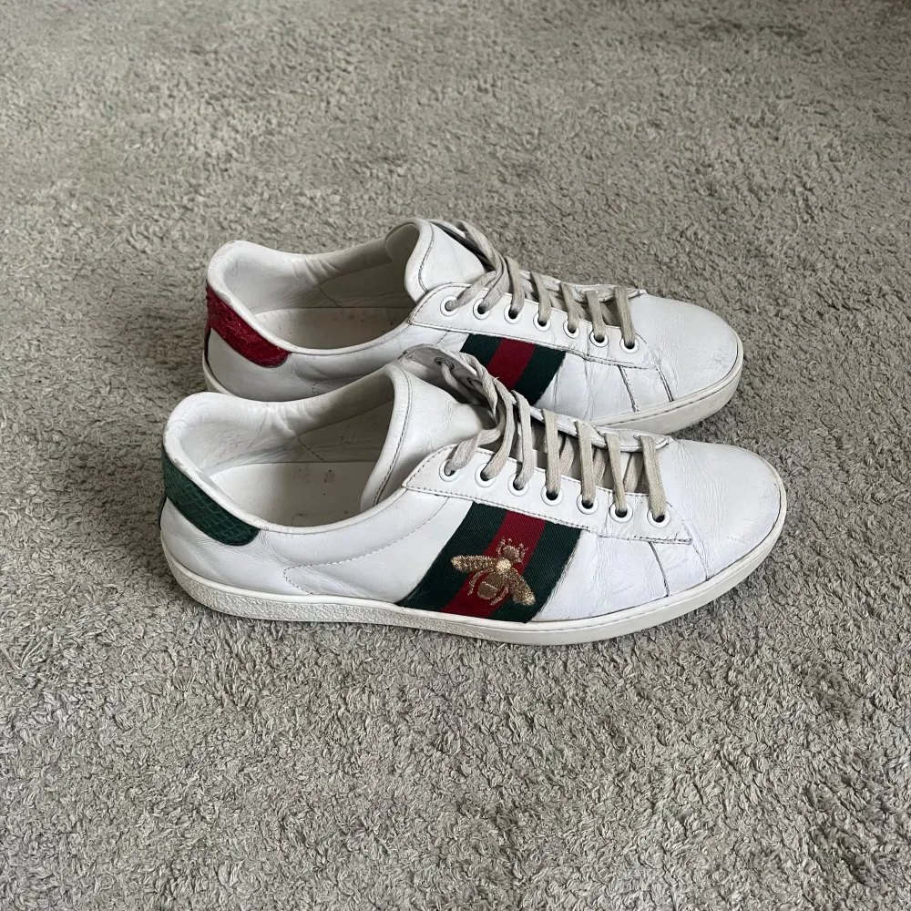 Ett par gucci ace skor. Storlek 41-42. Fint skick, bara lite sliten på baksidan av ena skon (se sista bild), och även lite slitna på framsidan av skon. Box och dustbag medföljer. Priset kan diskuteras. Hör av dig vid frågor eller funderingar. . Skor.